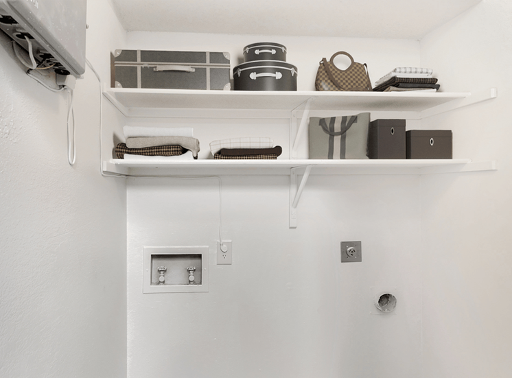 Laundry area with washer and dryer connections, shelves with bags and boxes